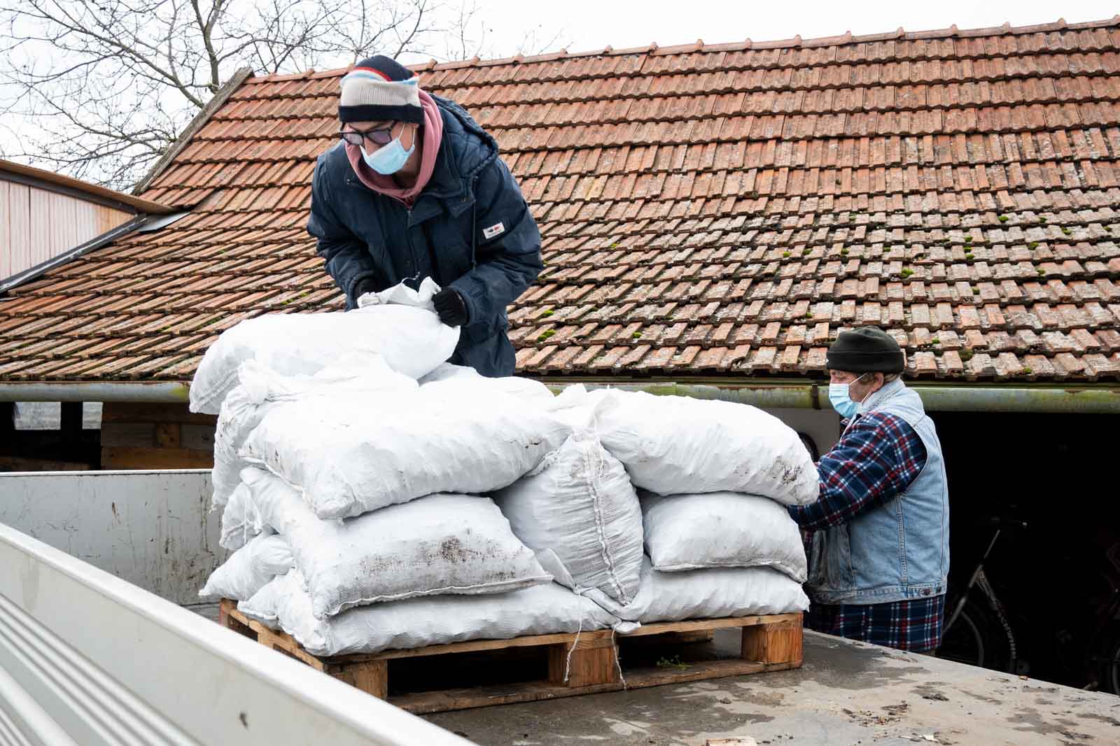 Az önkormányzati dolgozók lepakolják a barnakőszenet egy csabacsűdi családi ház udvarán (Fotó: Babák Zoltán)