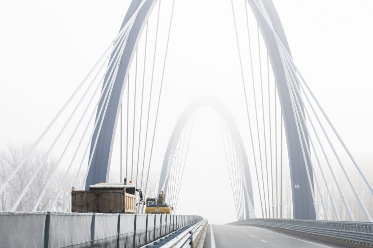 Munkagépek haladnak át angolosan az M44-es új Tisza-hídján 2021. december 15-én