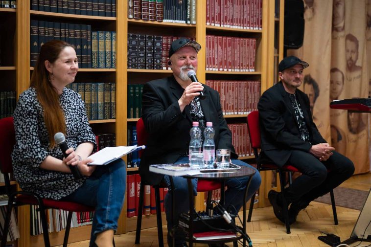 Turcsányi Lajos a Városi Könyvtárban 2022. május 2-án. Balról beszélgetőtársa, Hegedűs Éva, jobbról zenésztársa, Felföldi Zsolt.
