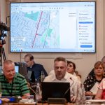 A Dózsa György és az Arany János utcák terve a kivetítőn, Moldován Attila tervező az előtérben a 2025. augusztus 28-i testületi ülésen.